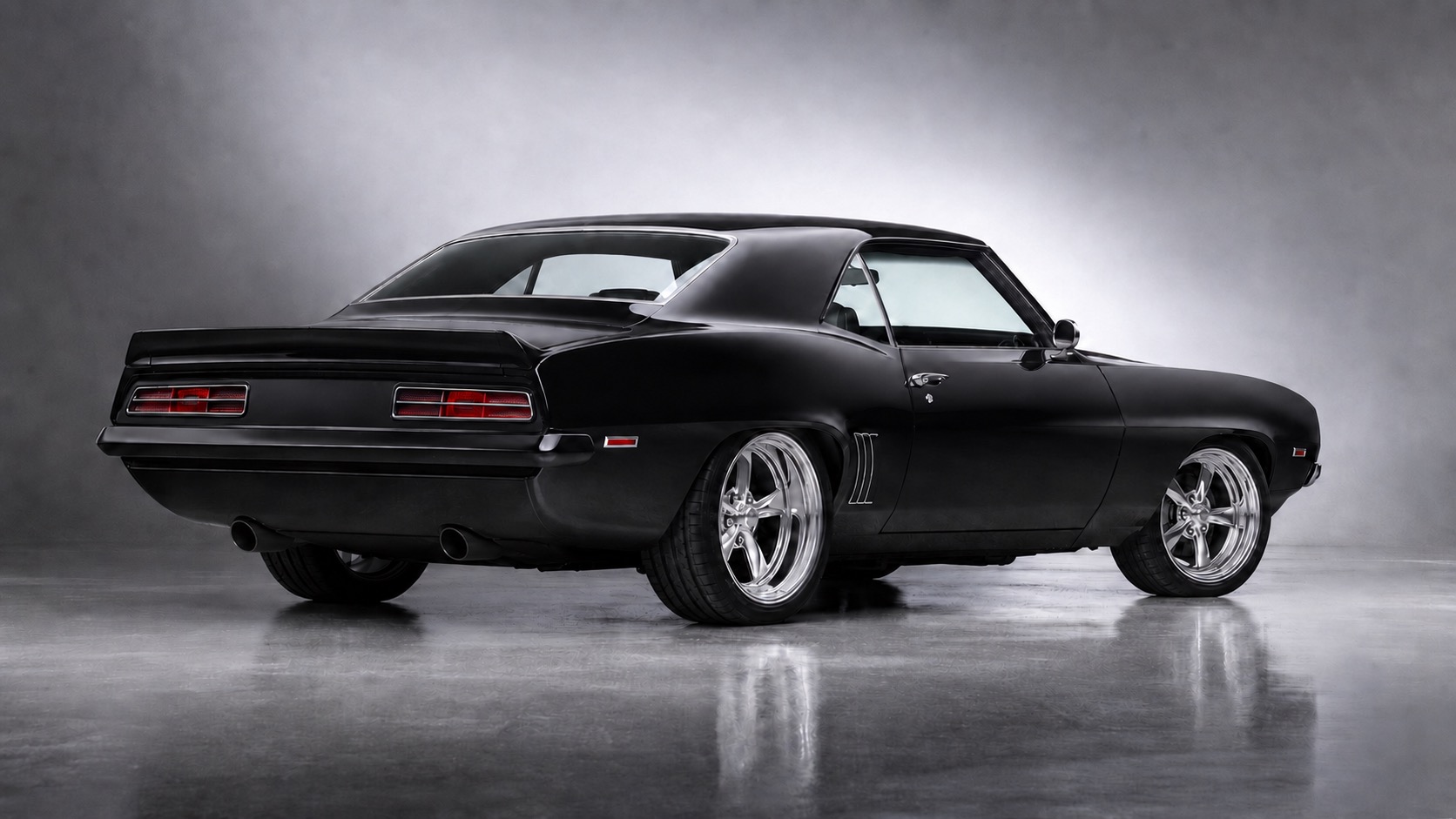 Blacked-out 1969 Chevrolet Camaro restomod, rear three-quarter view with polished five-spoke wheels and dual exhaust